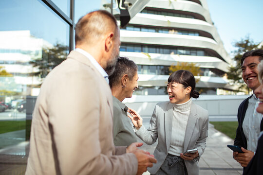 Business team networking outdoors near modern office building