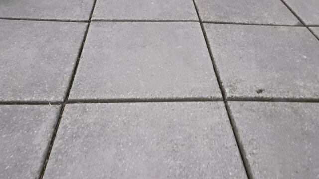 A close up of a sidewalk with a lot of concrete tiles on it