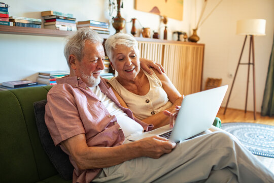 Senior couple reviewing utility bills at home with laptop
