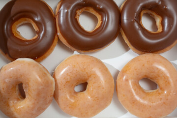 A top down view of a take out box of glazed and chocolate doughnut.