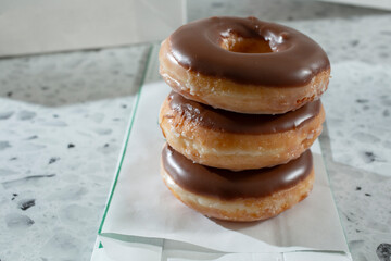 A view of a stack of chocolate iced glazed donuts.