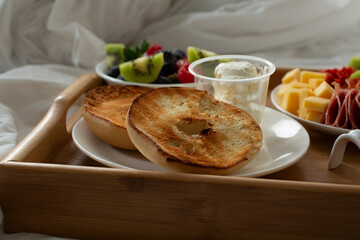 A view of a breakfast-in-bed tray, featuring bagels and cream cheese.