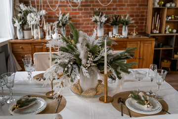 New Year's table setting in the kitchen with white plates on a gold napkins and a bouquet from the...