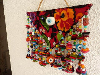 A vibrant handmade Turkish wall hanging with floral patterns, beads, and an evil eye for protection and cultural symbolism.