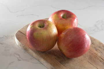 A view of some Fuji apples on a wood board.