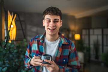 portrait of yong man stand with cup of coffee smile at home