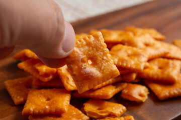 A view of a hand holding a popular cheesy crackers.