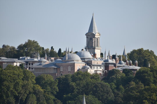 View of the majestic Topkapi Palace in Istanbul, featuring its iconic tower and domes nestled among greenery, representing Ottoman architectural grandeur
