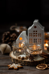 Aromatic christmas handmade candle with the sweet scent of gingerbread cookies. Cozy holiday home atmosphere, aromatherapy. Interior composition with burning candles, anise, cinnamon, pine cones