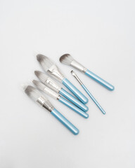 blue cosmetic brushes lie on a white background