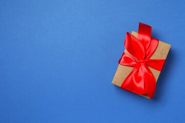 Beautiful gift box tied with bow on color background 