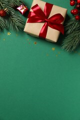 Beautiful gift box tied with bow and Christmas decorations on color background 