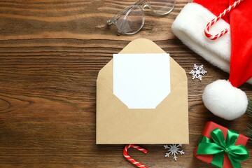 Festive Christmas composition with envelope, Santa hat and gift box on wooden background