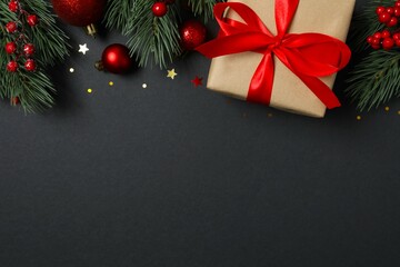 Beautiful gift box tied with bow and Christmas decorations on black background 