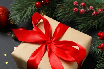 Beautiful gift box tied with bow and Christmas decorations on black background 