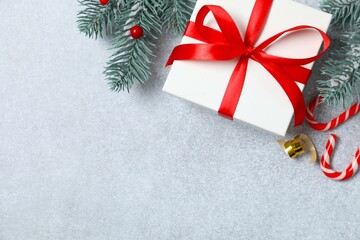 Beautiful gift box tied with bow and Christmas decorations on gray background 