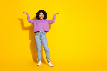 Full length photo of pretty young woman hold empty space isolated on yellow color background