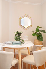 Living room with round table with four chairs. Table with natural and white wooden legs, golden...
