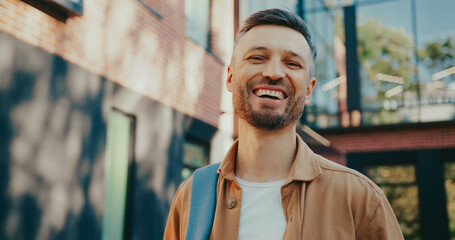 Portrait of bearded Caucasian man widely smiling to camera. Having good mood while spending time...