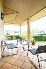 Terrace with porch in a country house, metal and black terrace table and chairs