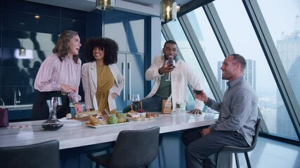 Two couples drink wine and eat in a modern kitchen in a high rise building 