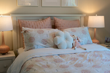 Adorable kids' bed with floral pastel bedding, decorative pillows, and a soft plush bunny toy, creating a cozy and inviting ambiance perfect for a children's room.