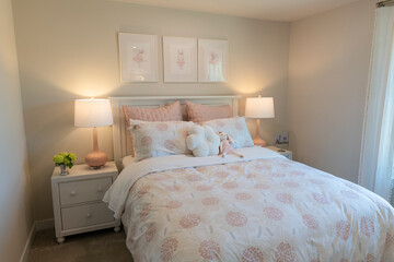Cozy kids' bedroom with pastel floral bedding, soft lighting, playful artwork, and a plush bunny toy, creating a warm and inviting space perfect for relaxation.