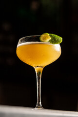 A glass of margarita cocktail with lime peel on a black background. Cold drink consisting of tequila and lime juice.