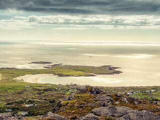 View from a mountain on Dogs bay in Connemara, county Galway, Ireland. Stunning Irish nature scene with ocean, beach and cloudy blue sky. Travel and tourism. Hiking in picturesque locations.