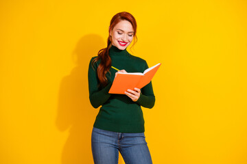 Photo of cheerful pretty lady dressed green jumper writing novel empty space isolated yellow color...