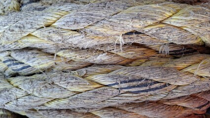 close-up of thick, intertwined yellow and brown ropes with visible texture and wear, showcasing their rugged and natural appearance