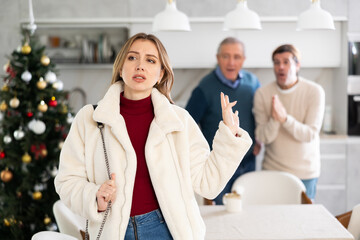 Fototapeta premium Elderly and adult men quarreling with young woman in kitchen at home