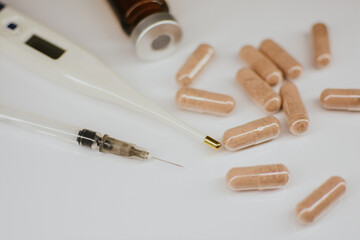 A syringe with a thin sharp needle, an injection ampoule, a thermometer and multi-colored tablets