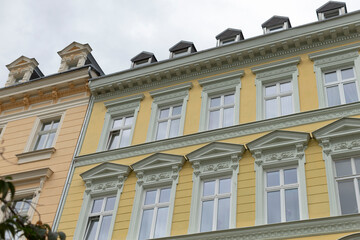 The facade of a preserved historic yellow building showcases its elegant decorative windows