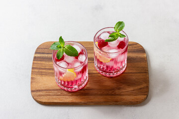 Raspberry cocktail with ice in a glass on a light background