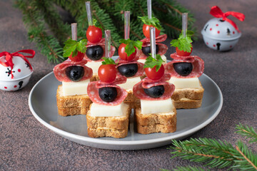 Canape with cherry tomatoes, sausage, cheese and black olives on gray plate