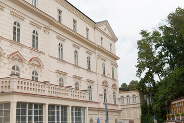 A historic buildings exterior is enhanced by a beautiful balcony and trees in the background