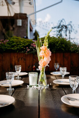 Elegant table setting with gladiolus flowers in vase under natural light, perfect for outdoor dining