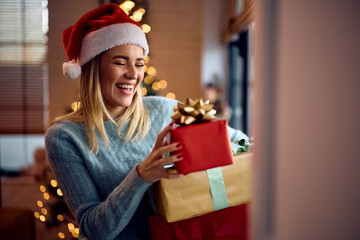 Joyful woman having fun with Christmas presents at home.