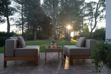 A cozy seating area with comfy cushions, a table, and a beautiful sunset view in a tranquil garden