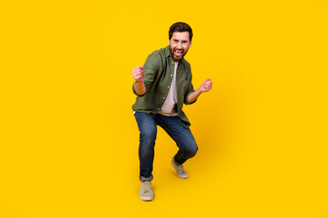 Full size photo of nice young man dance raise fists wear shirt isolated on yellow color background