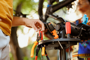 Close-up of healthy man outdoors selecting expert work tools from toolbox for bike maintenance. Up-close perspective of male caucasian hand organizing specialized equipment for servicing bicycle.