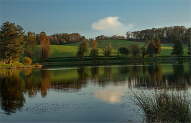 Autumn reflections in a lake with one lone cloud in the sky