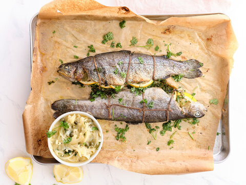 Top view of whole grilled white fish with lemon, parsley and onion sauce