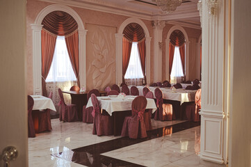 an empty hall is a classic restaurant with curtains white tablecloths and Romanesque decor. High quality photo