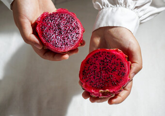 dragon fruit, also known as pitaya, cut open pink magenta-colored flesh with tiny black seeds, tropical fruits