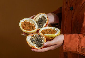 hand holding freshly cut passion fruit (Passiflora edulis and Passiflora ligularis), revealing its vibrant, juicy orange pulp filled with glossy seeds