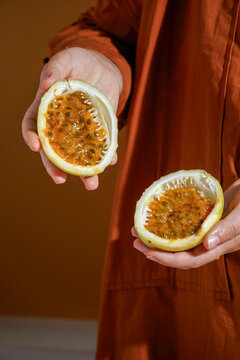 hand holding freshly cut passion fruit (Passiflora edulis and Passiflora ligularis), revealing its vibrant, juicy orange pulp filled with glossy seeds