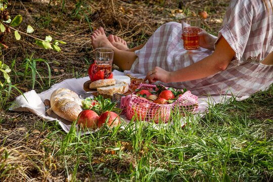 life view, young girl picnic scene featuring fresh pomegranates, walnuts, pine nuts, and creamy white cheese displayed on a wooden board, natural sunlight pomegranate garden