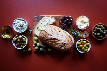 Selection of olive produce including kalamata olive sourdough bread, green olive dip, olive oil, olive dairy free spread, Sicilian olives, and marinated green and black olives.